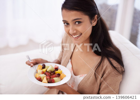 Happy woman, portrait and bowl of fruit in diet, nutrition or healthy snack on sofa at home. Face of young female person, nutritionist or vegan smile and eating breakfast for vitamin c, salad or meal 139606421