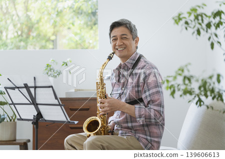 Portrait of a smiling man in his 60s holding a saxophone. Portrait of a smiling man in his 60s holding a saxophone. 139606613