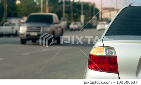 Close-up shot focused on the rear right taillight of a silver sedan. With turn signal Background shows a blurry pickup truck and a clear road surface. Emphasizing the vehicle's design and lighting. Close-up shot focused on the rear right taillight of a silver sedan. With turn signal Background shows a blurry pickup truck and a clear road surface. Emphasizing the vehicle's design and lighting. 139606637