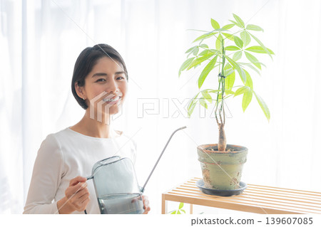 一位女士正在用澆水壺給室內植物澆水。 一位女士正在用澆水壺給室內植物澆水。 139607085