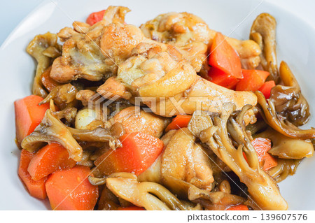 Braised chicken wings and carrots, a Japanese-style stew with mushrooms, against a white background. Braised chicken wings and carrots, a Japanese-style stew with mushrooms, against a white background. 139607576