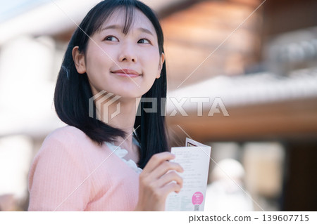 A woman enjoys sightseeing in Kawagoe, the "Little Edo" town, with the town's bell tower in the background, holding a pamphlet as she walks through the streets. (Saitama, tourist image) A woman enjoys sightseeing in Kawagoe, the "Little Edo" town, with the town's bell tower in the background, holding a pamphlet as she walks through the streets. (Saitama, tourist image) 139607715