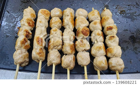 Thai Style Grilled Pork Meatballs Skewers Cooking on a Hot Flat Griddle Pan 139608221