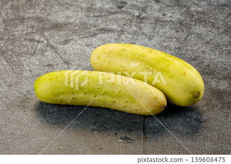 Two whole ripe white cucumbers on a dark textured stone background. Two whole ripe white cucumbers on a dark textured stone background. 139608475