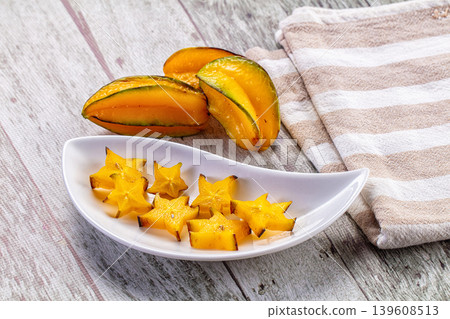 Fresh sliced star fruit and whole carambola on a plate over a rustic wooden background. Fresh sliced star fruit and whole carambola on a plate over a rustic wooden background. 139608513