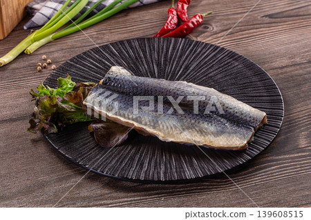 Salted herring fillets served on a white dish with lettuce and green onions 139608515