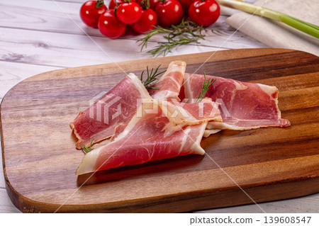 Gourmet prosciutto slices cherry tomatoes garlic rosemary green onion wooden board Gourmet prosciutto slices cherry tomatoes garlic rosemary green onion wooden board 139608547