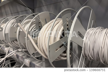 Row of large spools with white electric cable on a shelf in a hardware store or warehouse Row of large spools with white electric cable on a shelf in a hardware store or warehouse 139608731