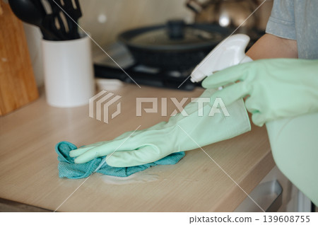 Hand in green rubber glove washing kitchen countertop with sponge, hygiene and home sanitation concept Hand in green rubber glove washing kitchen countertop with sponge, hygiene and home sanitation concept 139608755