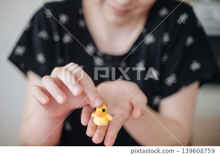 Little girl holding small handmade yellow modeling clay figurine, child creativity and fine motor skills Little girl holding small handmade yellow modeling clay figurine, child creativity and fine motor skills 139608759