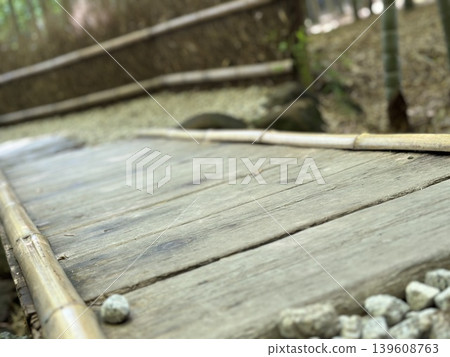 A traditional Japanese wooden bridge and gravel path nestled in a bamboo grove; a landscape photograph evoking the tranquility of a Japanese garden. A traditional Japanese wooden bridge and gravel path nestled in a bamboo grove; a landscape photograph evoking the tranquility of a Japanese garden. 139608763