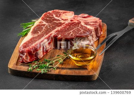 Raw porterhouse t bone steaks with olive oil and herbs on wooden board Raw porterhouse t bone steaks with olive oil and herbs on wooden board 139608769