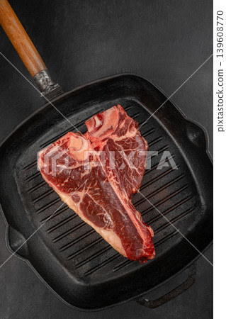 Raw porterhouse t bone steak in cast iron grill pan on dark background 139608770