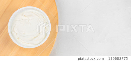 Cream cheese spread in plastic container on wooden board with copy space 139608775