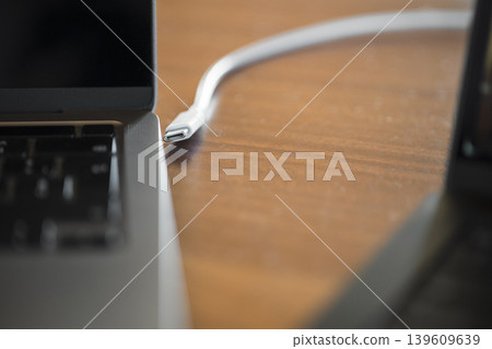 USB C Cable Connected to Laptop on Wooden Desk USB C Cable Connected to Laptop on Wooden Desk 139609639