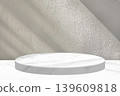 Minimalist White Marble Product Display Podium Set Against Textured Plaster Wall with Light Flare 139609818