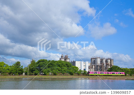 A train running through a blue sky and an industrial area. A train running through a blue sky and an industrial area. 139609857