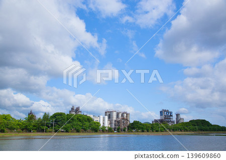 A train running through a blue sky and an industrial area. A train running through a blue sky and an industrial area. 139609860