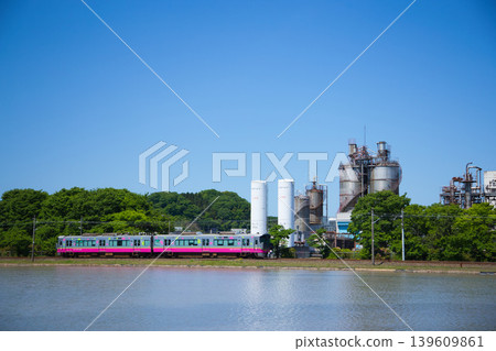 A train running through a blue sky and an industrial area. A train running through a blue sky and an industrial area. 139609861