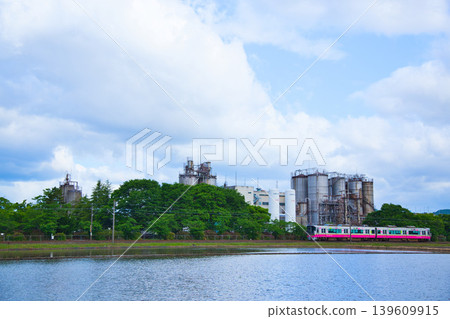 A train running through a blue sky and an industrial area. A train running through a blue sky and an industrial area. 139609915