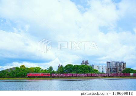 A train running through a blue sky and an industrial area. A train running through a blue sky and an industrial area. 139609918