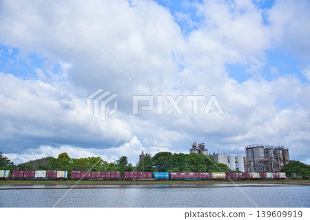 A train running through a blue sky and an industrial area. A train running through a blue sky and an industrial area. 139609919