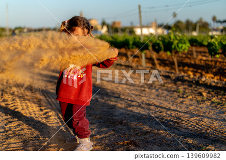 Child having fun throwing soil in the air at sunset. Child having fun throwing soil in the air at sunset. 139609982