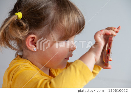 Young girl making a photo with her smartphone, exploring digital tools at early age. 139610022