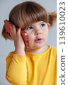 A toddler girl speaking on a smartphone, reflecting childhood interaction with modern devices. 139610023