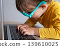A toddler typing and looking very closed at a screen, with the potential risks to eye health that exposure to electronic devices entails. 139610025