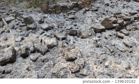 Fire aftermath showing ash covered land with broken stones Fire aftermath showing ash covered land with broken stones 139610182