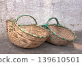 Traditional Woven Baskets on Rustic Wall.Hand-woven wicker baskets with vibrant green trim resting against a distressed, textured background, perfect for themes of craft, culture, and rustic living. 139610501