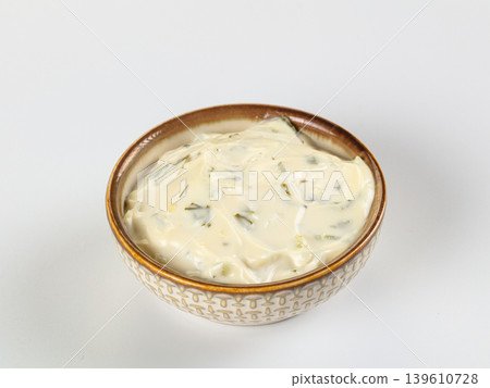 Creamy tartar sauce with herbs and pickles in a patterned ceramic bowl isolated on white Creamy tartar sauce with herbs and pickles in a patterned ceramic bowl isolated on white 139610728