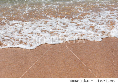 Gentle ocean waves washing onto sandy beach with soft sea foam and natural coastal texture creating peaceful tropical seaside atmosphere Gentle ocean waves washing onto sandy beach with soft sea foam and natural coastal texture creating peaceful tropical seaside atmosphere 139610860