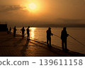 Sunrise silhouettes of fishermen by the sea. Atmospheric coastal morning scene with amateur fishermen silhouettes at sunrise. 139611158