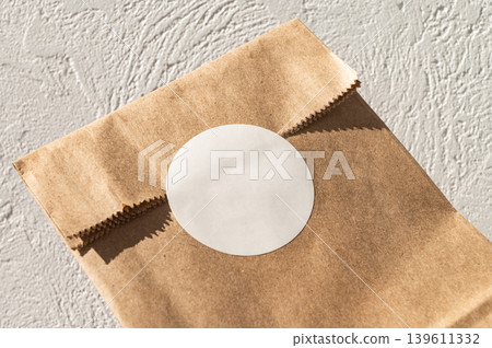 Brown paper bag with white circular sticker on textured surface Brown paper bag with white circular sticker on textured surface 139611332
