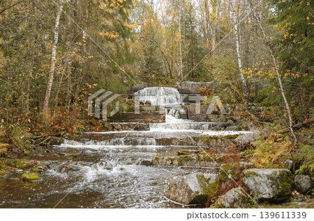 Peaceful forest waterfall in autumn with mossy rocks and colorful foliage Peaceful forest waterfall in autumn with mossy rocks and colorful foliage 139611339