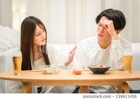 一個男人在餐桌旁垂頭喪氣,一個女人關切地和他說話。 一個男人在餐桌旁垂頭喪氣,一個女人關切地和他說話。 139611456