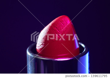 Vibrant magenta lipstick closeup under studio spotlight sleek commercial frame highlights rich pigment and glossy sheen on red magenta bullet with deep purple background Vibrant magenta lipstick closeup under studio spotlight sleek commercial frame highlights rich pigment and glossy sheen on red magenta bullet with deep purple background 139611795