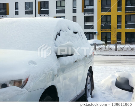 Snow is piled high on the roofs of parked cars in a parking lot Snow is piled high on the roofs of parked cars in a parking lot 139611960