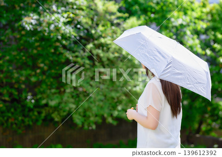 一位二十多歲的女子撐著陽傘。 一位二十多歲的女子撐著陽傘。 139612392