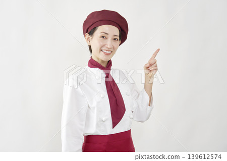 A female pastry chef points to the right. A female pastry chef points to the right. 139612574