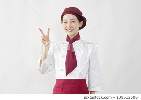 A smiling pastry chef makes a peace sign. A smiling pastry chef makes a peace sign. 139612590