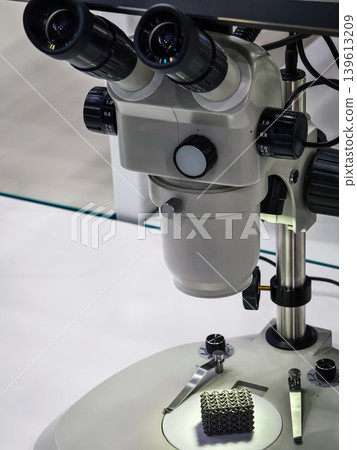 Microscope used for examining small objects in a laboratory setting with focus on a textured sample underneath Microscope used for examining small objects in a laboratory setting with focus on a textured sample underneath 139613209