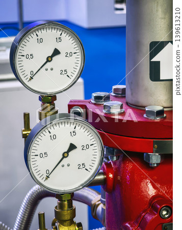 Pressure gauges show readings on a red system in a workshop setting with a blue background Pressure gauges show readings on a red system in a workshop setting with a blue background 139613210