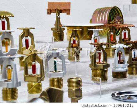Various types of fire sprinkler heads displayed in a workshop setting during daytime Various types of fire sprinkler heads displayed in a workshop setting during daytime 139613212