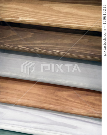 Wooden planks showing different colors and textures arranged in layers at a workshop during daytime Wooden planks showing different colors and textures arranged in layers at a workshop during daytime 139613213
