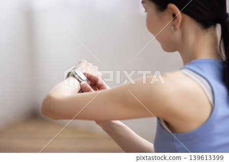 Japanese woman in yoga wear looking at a smartwatch Japanese woman in yoga wear looking at a smartwatch 139613399