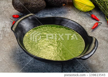 Green Spinach vegetable soup in a bowl with fresh avocado and chili peppers 139613543
