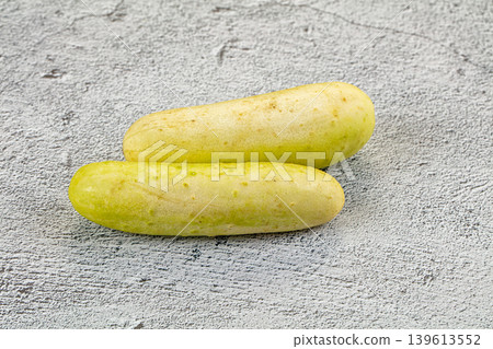 Two whole ripe white cucumbers on a dark textured stone background. Two whole ripe white cucumbers on a dark textured stone background. 139613552